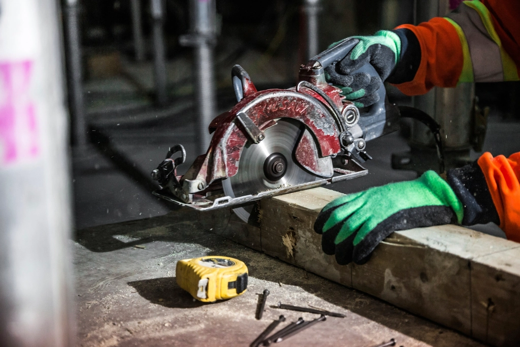 Tradesperson cutting timber with a power saw on site