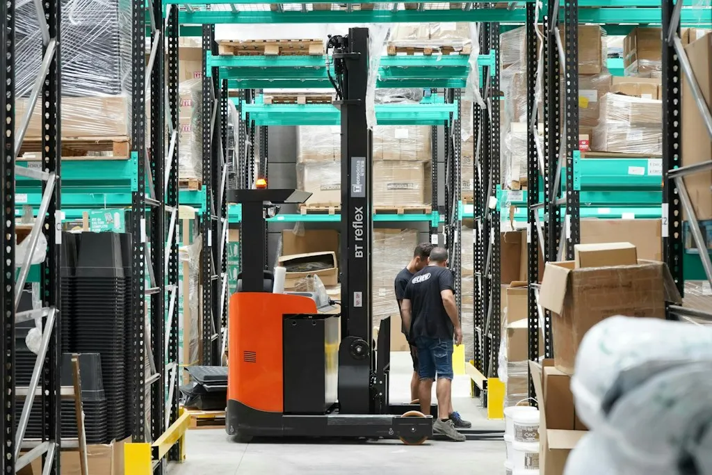 Warehouse worker beside a reach truck forklift
